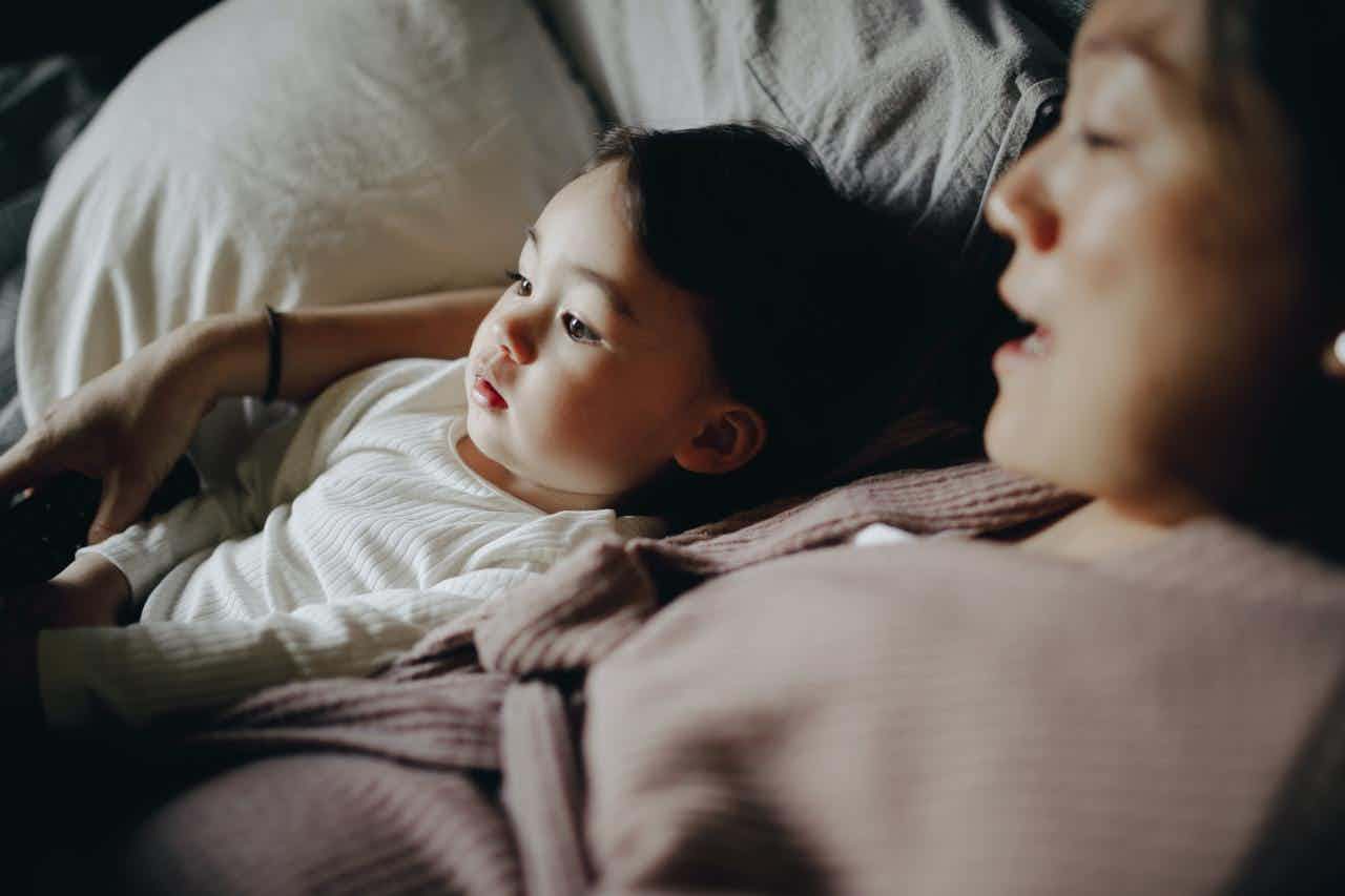 A mother and child relax in bed. 