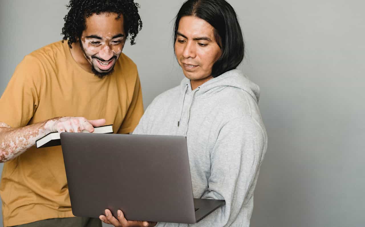 Two men are looking and pointing at a laptop.