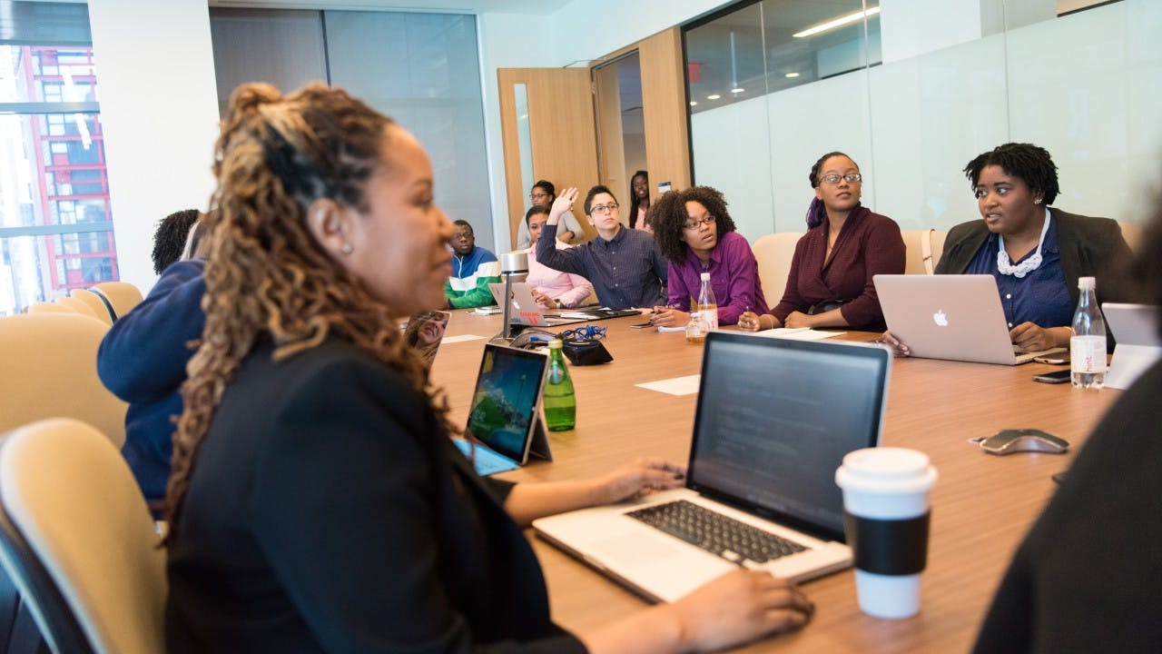 A group of diverse coworkers sit around a conference table during a meeting.