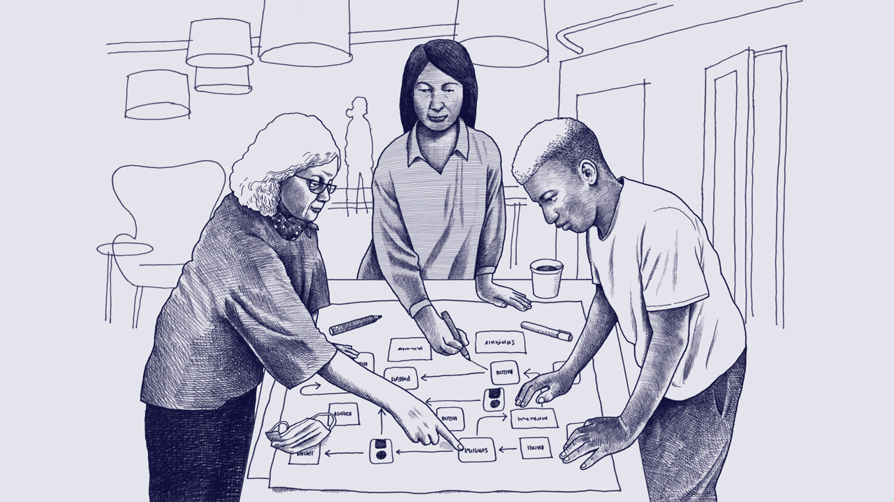 An older white woman, a middle-aged Native American woman, and a young Black man stand together at a table and point to a flow chart. 
