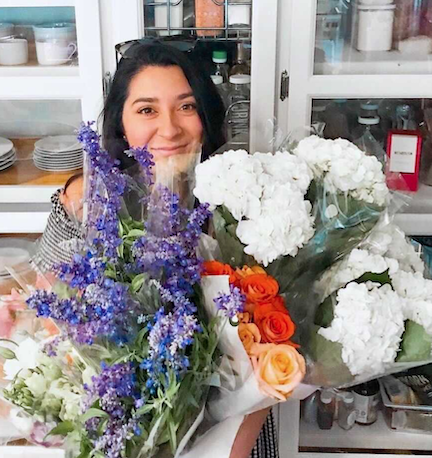 A photo of Lauren Bermudez holding bouquets of flowers.