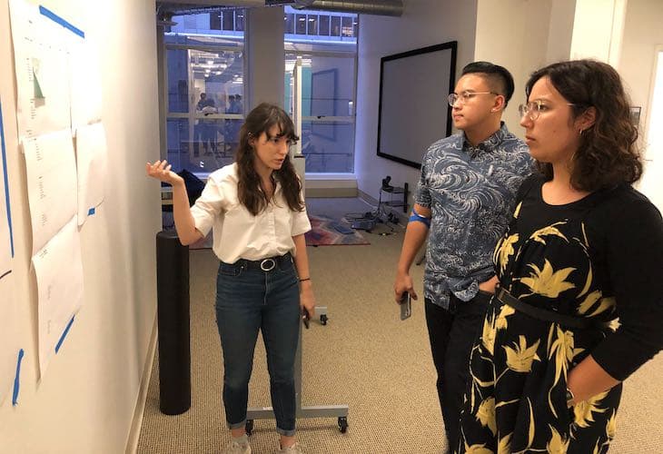 Three Nava staff looking at whiteboard and talking.