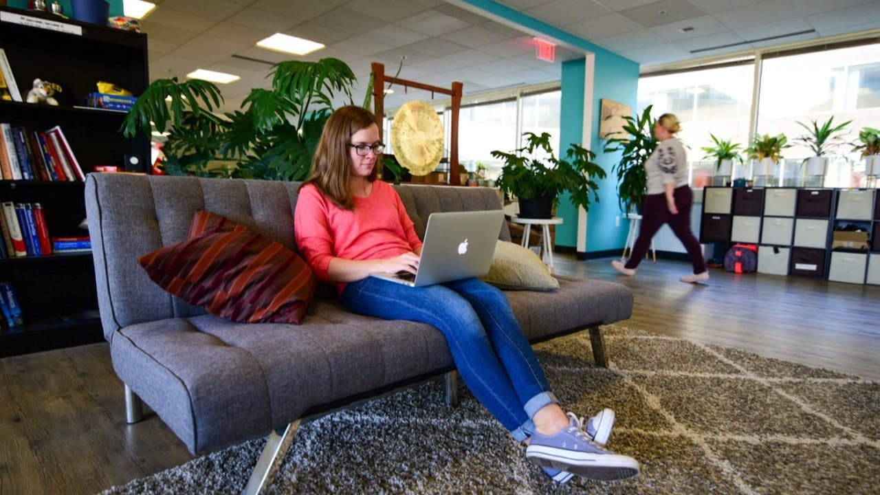 A picture of software engineer Sharon Warner working on a laptop on a couch in Nava's DC office.